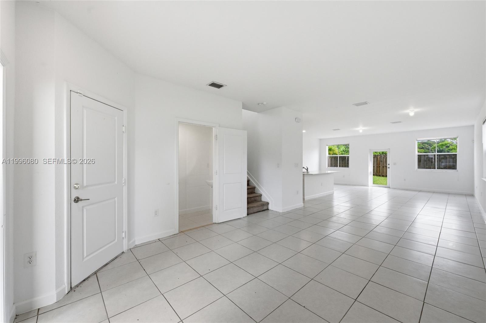 An open-concept living area features white walls, tile flooring, a kitchen, and a staircase — 2345 NW 131st Cir # 2345, Miami FL 33167, MIAMI, FL