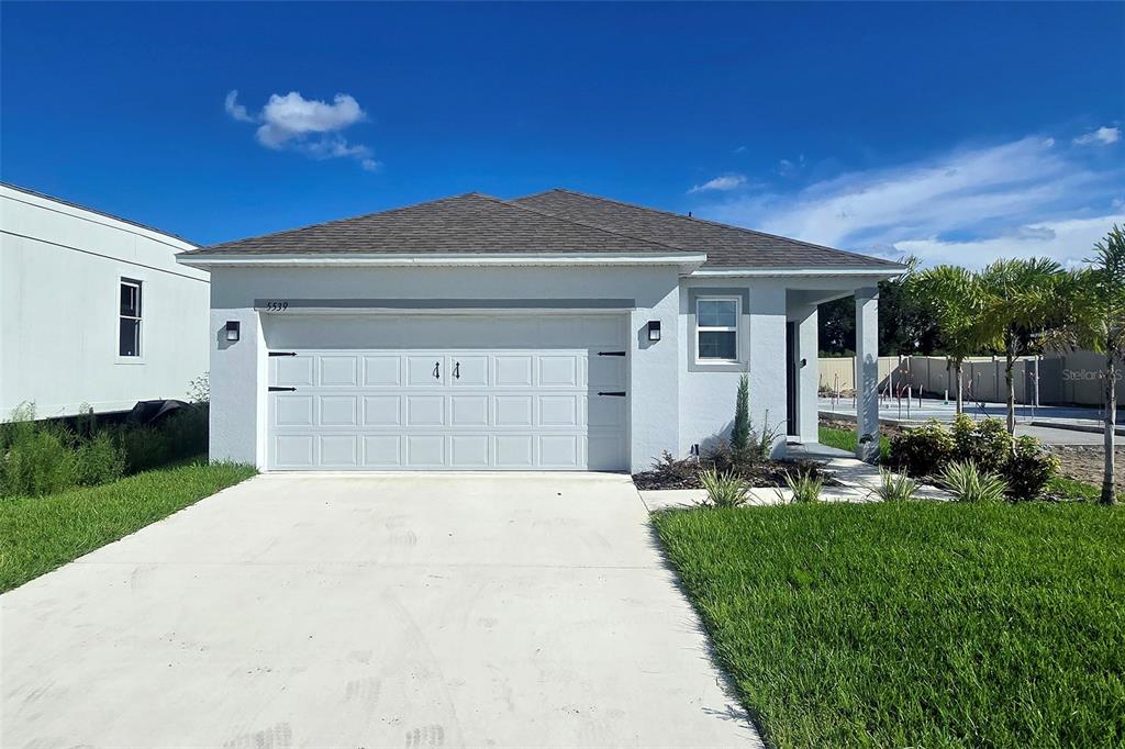 A single-story house with a white stucco exterior, a two-car garage, and a concrete driveway — 5539 MADDIE DRIVE, HAINES CITY, FL