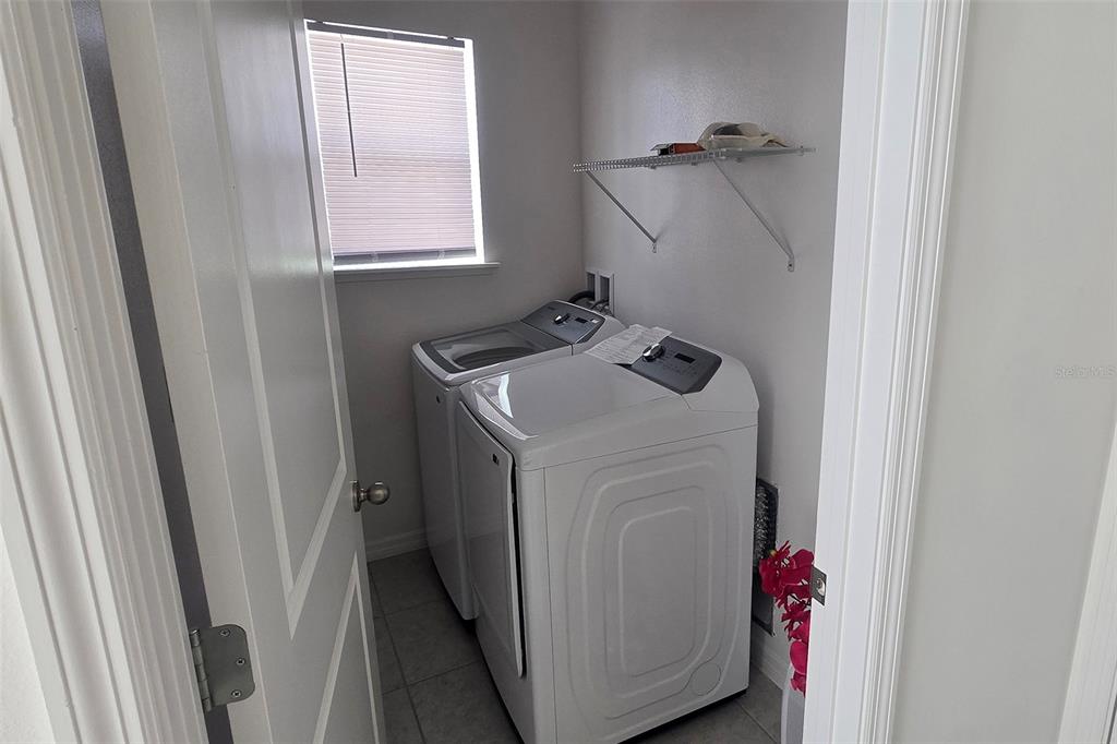 A laundry room features a white washer and dryer, a window, and a wire shelf — 5539 MADDIE DRIVE, HAINES CITY, FL