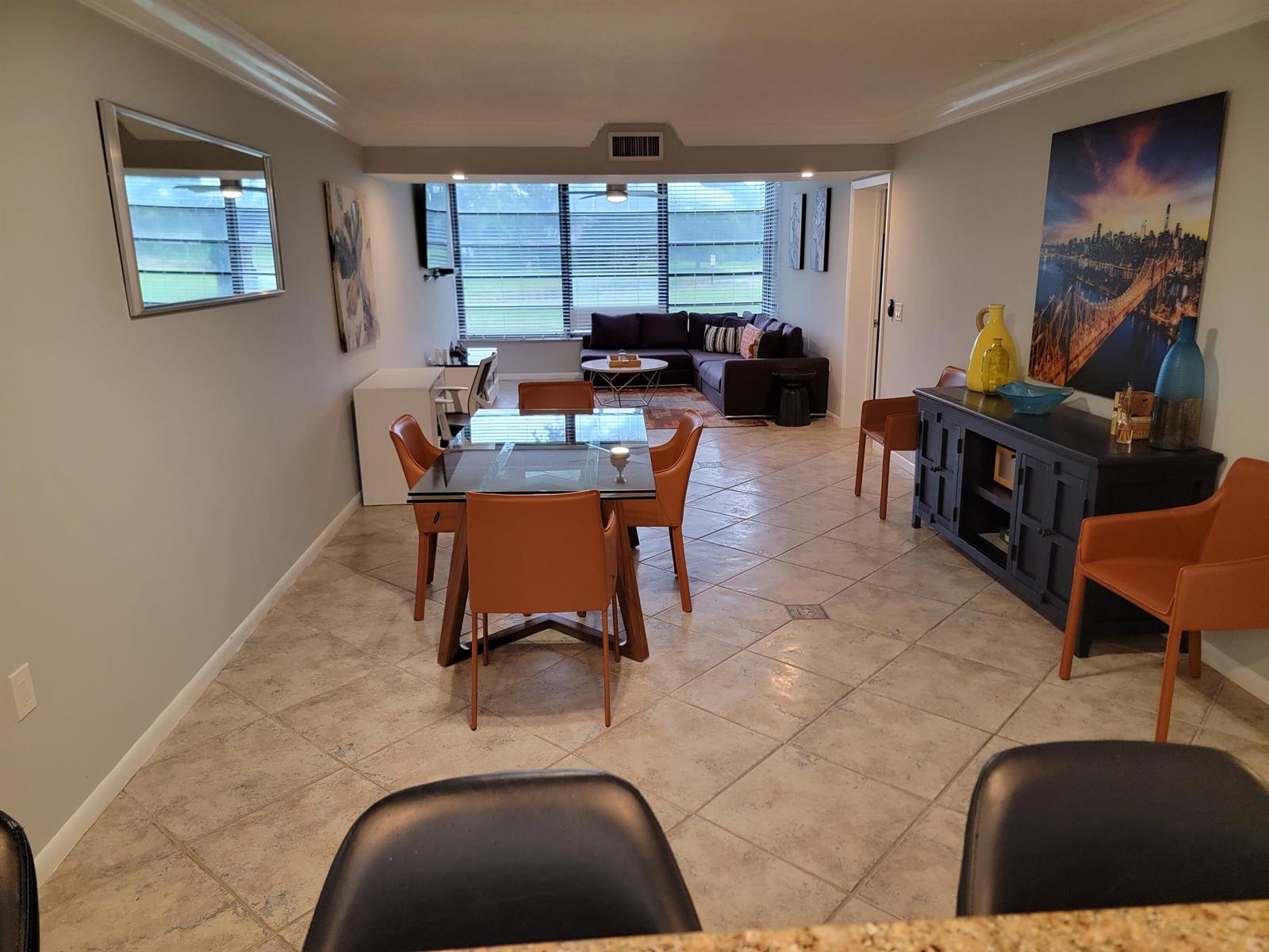 An open-concept living and dining area features tile flooring, a glass dining table, and furniture — 3540 Whitehall Drive # 106, West Palm Beach FL 33401, WEST PALM BEACH, FL