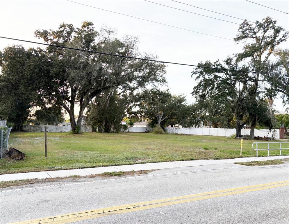 A vacant, grassy lot with mature trees is bordered by a white fence — 6227 KRYCUL AVENUE, RIVERVIEW, FL