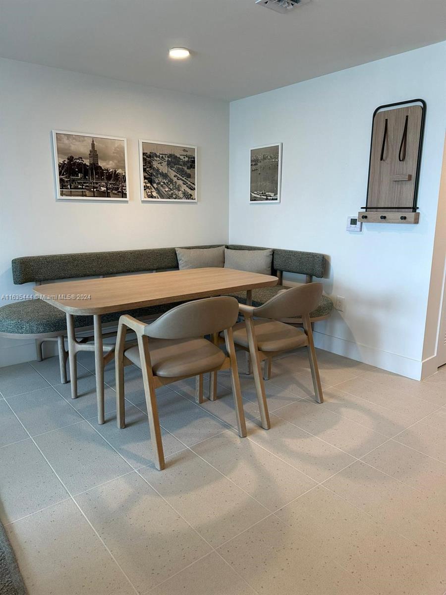 A dining area features a corner banquette, a wooden table, two chairs, and wall art — 159 NE 6 th Street # 3513, Miami FL 33132, MIAMI, FL
