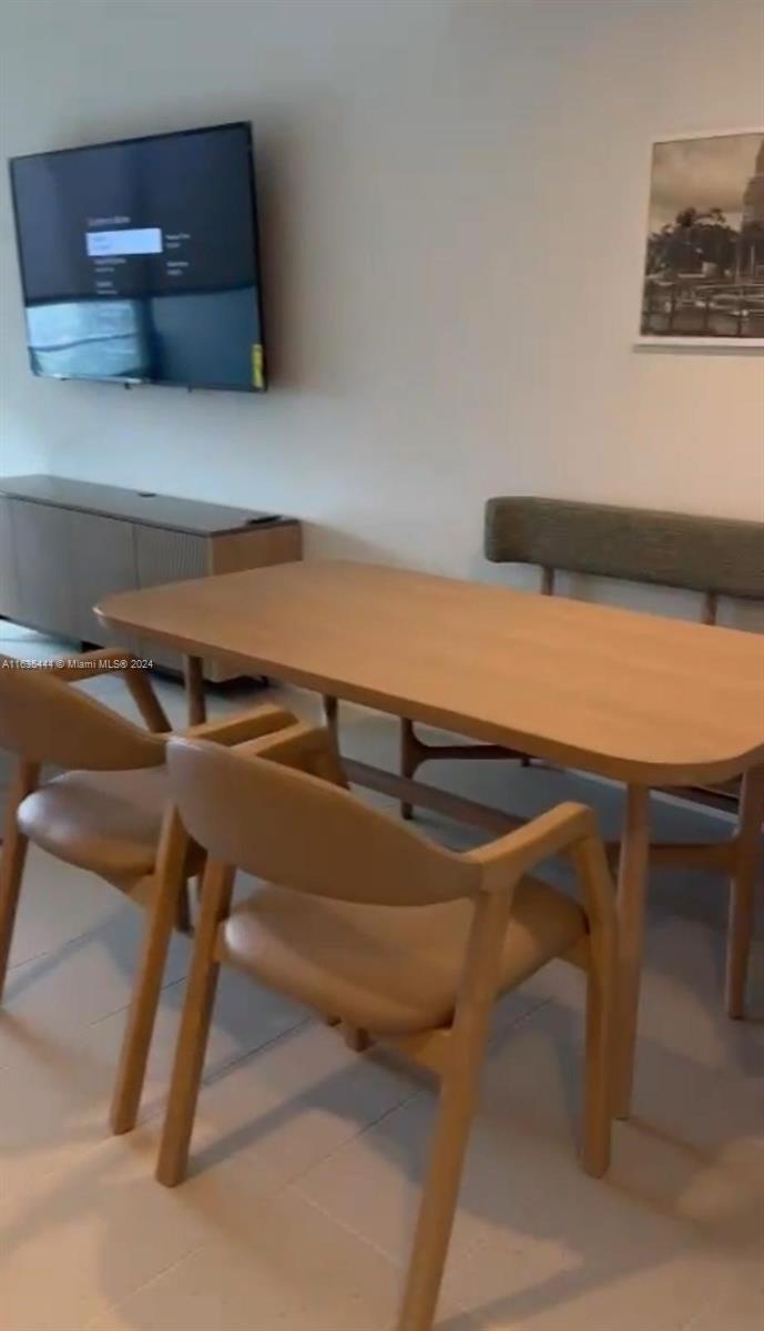 A dining area features a wooden table, matching chairs, a bench, and a wall-mounted television — 159 NE 6 th Street # 3513, Miami FL 33132, MIAMI, FL