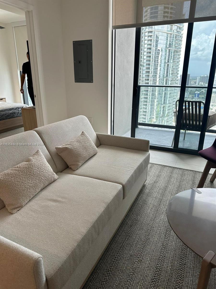 A living room features a beige sofa, a round table, and a balcony with city views — 159 NE 6 th Street # 3513, Miami FL 33132, MIAMI, FL
