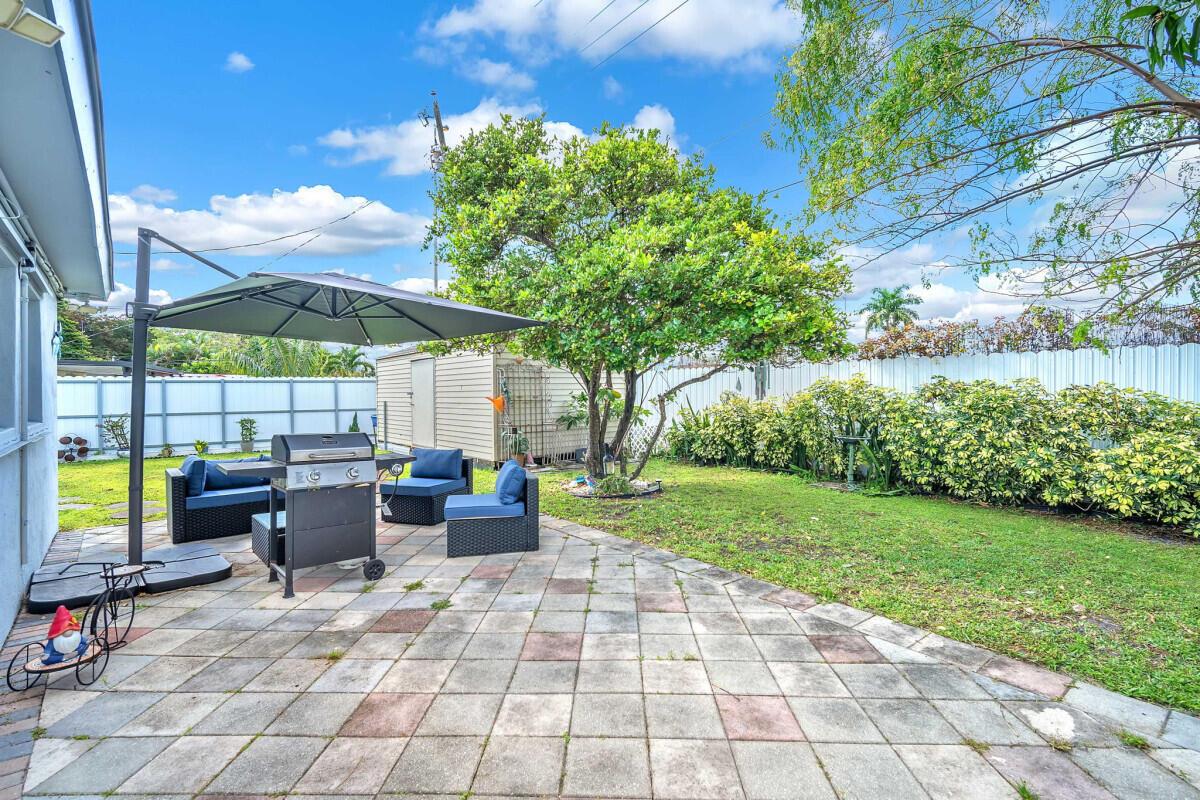 A backyard patio features a grill, outdoor seating, a large umbrella, and a storage shed — 404 S 62nd Terrace, Hollywood FL 33023, HOLLYWOOD, FL