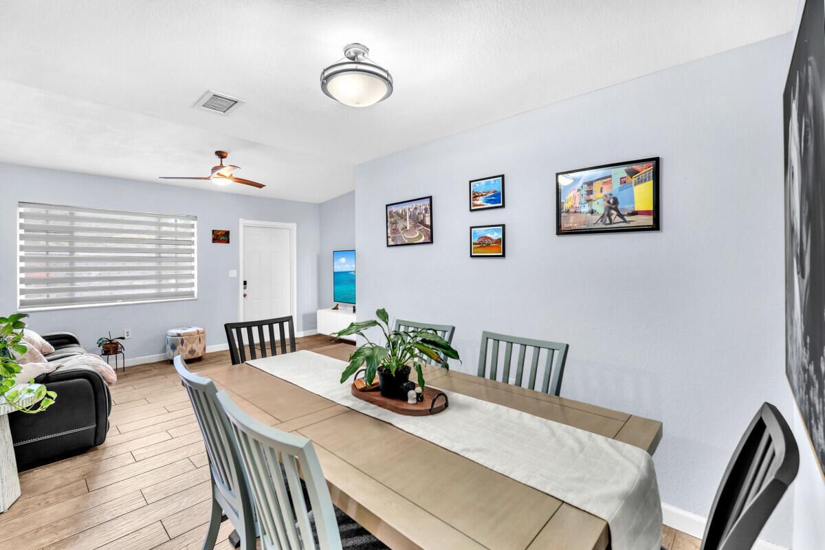 A dining room features a wooden table, grey chairs, and framed wall art — 404 S 62nd Terrace, Hollywood FL 33023, HOLLYWOOD, FL