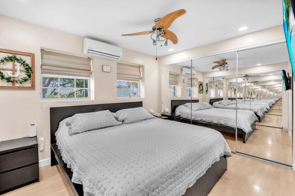 A bedroom features a bed, mirrored closet doors, a ceiling fan, and two windows — 404 S 62nd Terrace, Hollywood FL 33023, HOLLYWOOD, FL