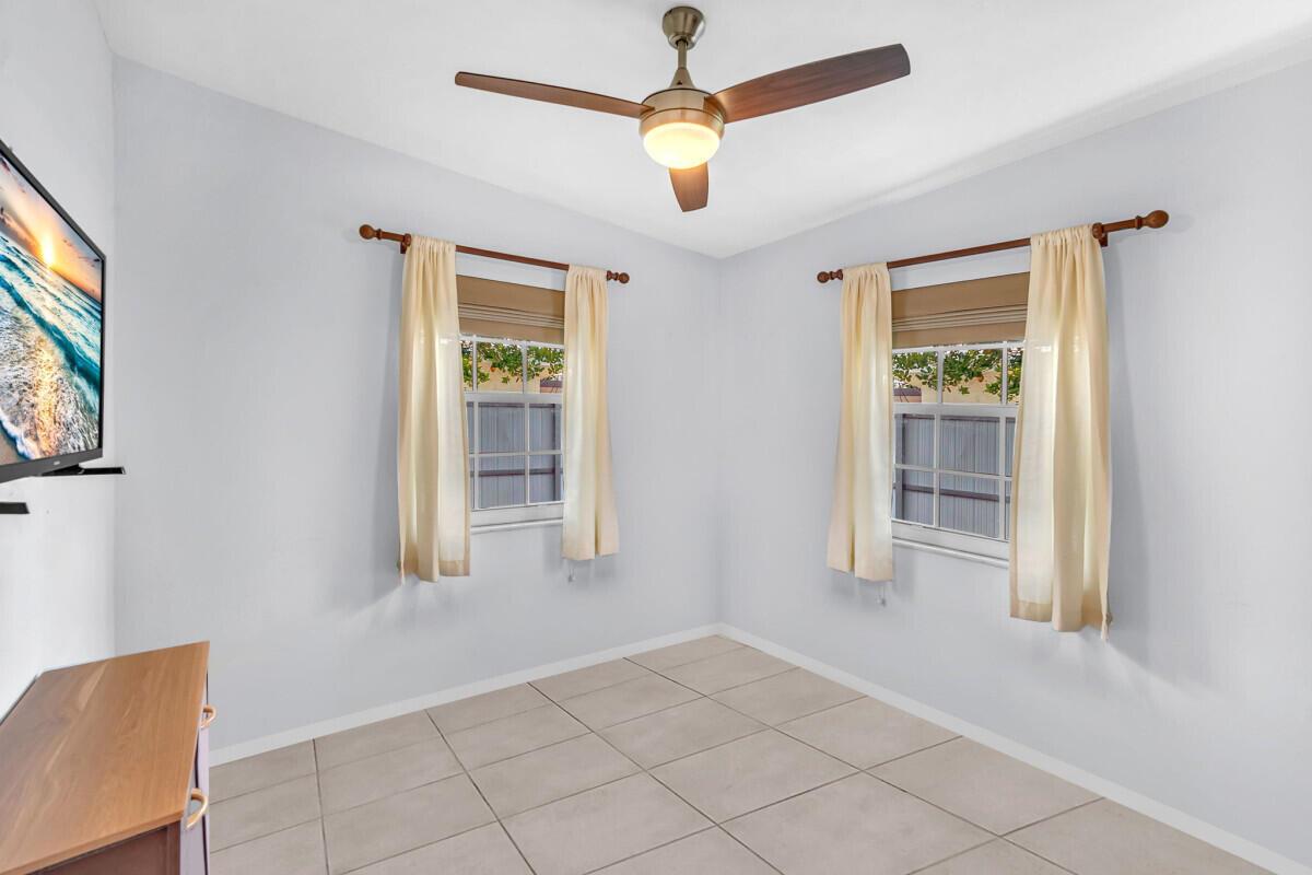 An empty room features light-colored tile flooring, two windows with curtains, and a ceiling fan — 404 S 62nd Terrace, Hollywood FL 33023, HOLLYWOOD, FL