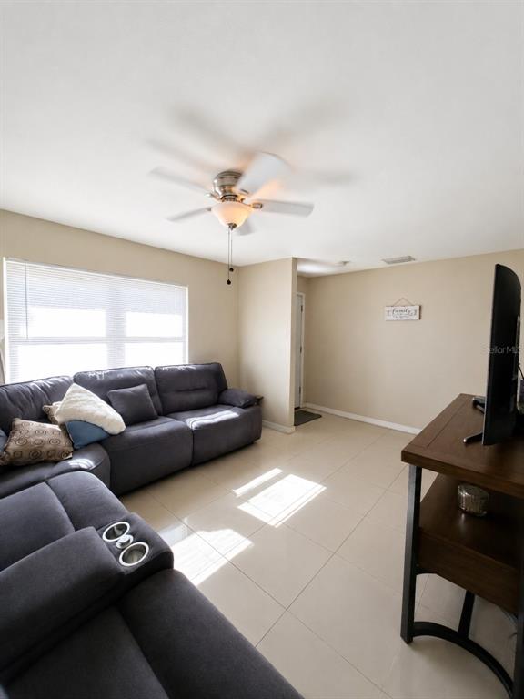 A living room features a grey sectional sofa, tile flooring, and a ceiling fan — 5814 HAMMON DRIVE, TAMPA, FL