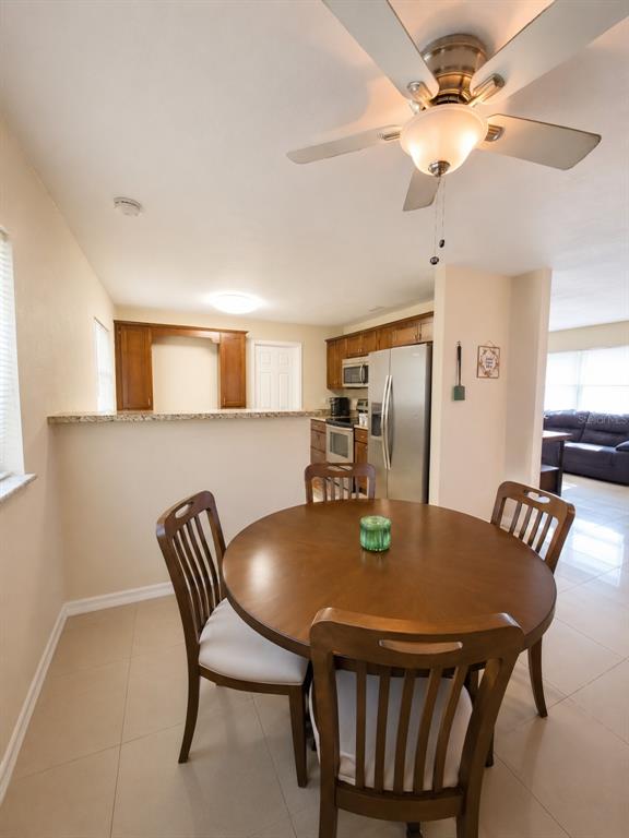 A dining area with a round wooden table and four chairs sits before a kitchen — 5814 HAMMON DRIVE, TAMPA, FL