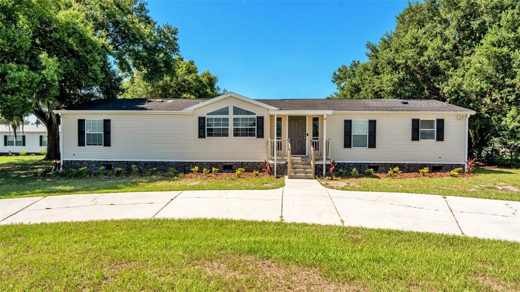 A single-story manufactured home with light siding, a dark roof, and a concrete driveway — 8045 ALTURAS BABSON PARK CUTOFF, BARTOW, FL