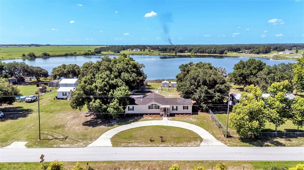 An aerial view shows a single-story house with a curved driveway facing a large lake — 8045 ALTURAS BABSON PARK CUTOFF, BARTOW, FL