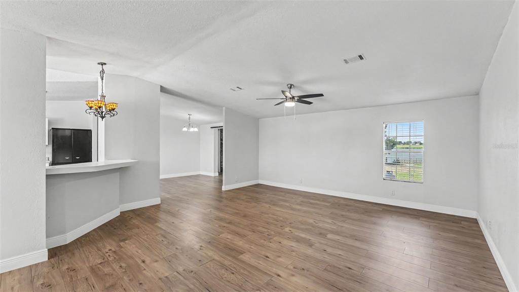 A spacious living room features light wood-look flooring, a ceiling fan, and a breakfast bar — 8045 ALTURAS BABSON PARK CUTOFF, BARTOW, FL