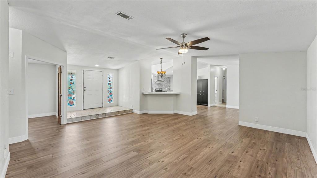An open-concept living area features wood-look flooring, a ceiling fan, and a raised entryway — 8045 ALTURAS BABSON PARK CUTOFF, BARTOW, FL