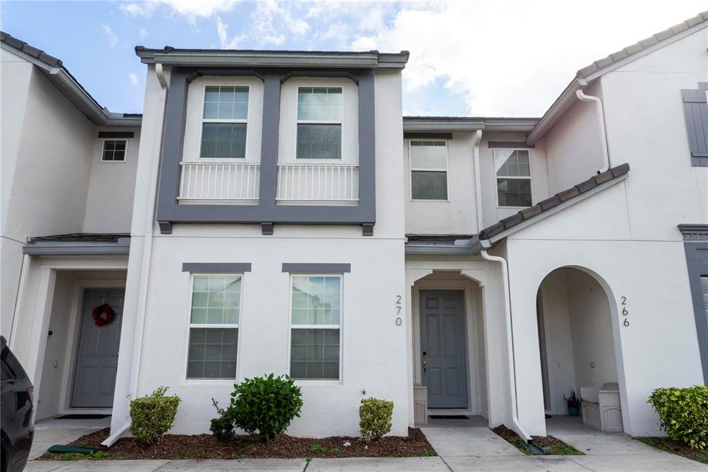A two-story townhouse exterior with white stucco walls, gray trim, and two front entrances — 270 CAPTIVA DRIVE, DAVENPORT, FL