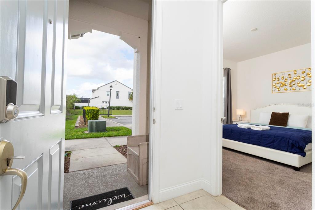 An open front door reveals a porch, a neighborhood view, and an adjacent bedroom — 270 CAPTIVA DRIVE, DAVENPORT, FL