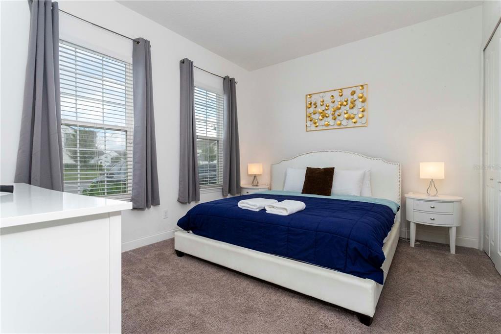 A bedroom features a bed with a blue quilt, two windows, and white nightstands — 270 CAPTIVA DRIVE, DAVENPORT, FL