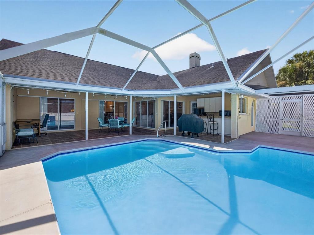 A swimming pool sits inside a screened-in patio area attached to a single-story house — 1197 MUSCOVY DR, SPRING HILL, FL