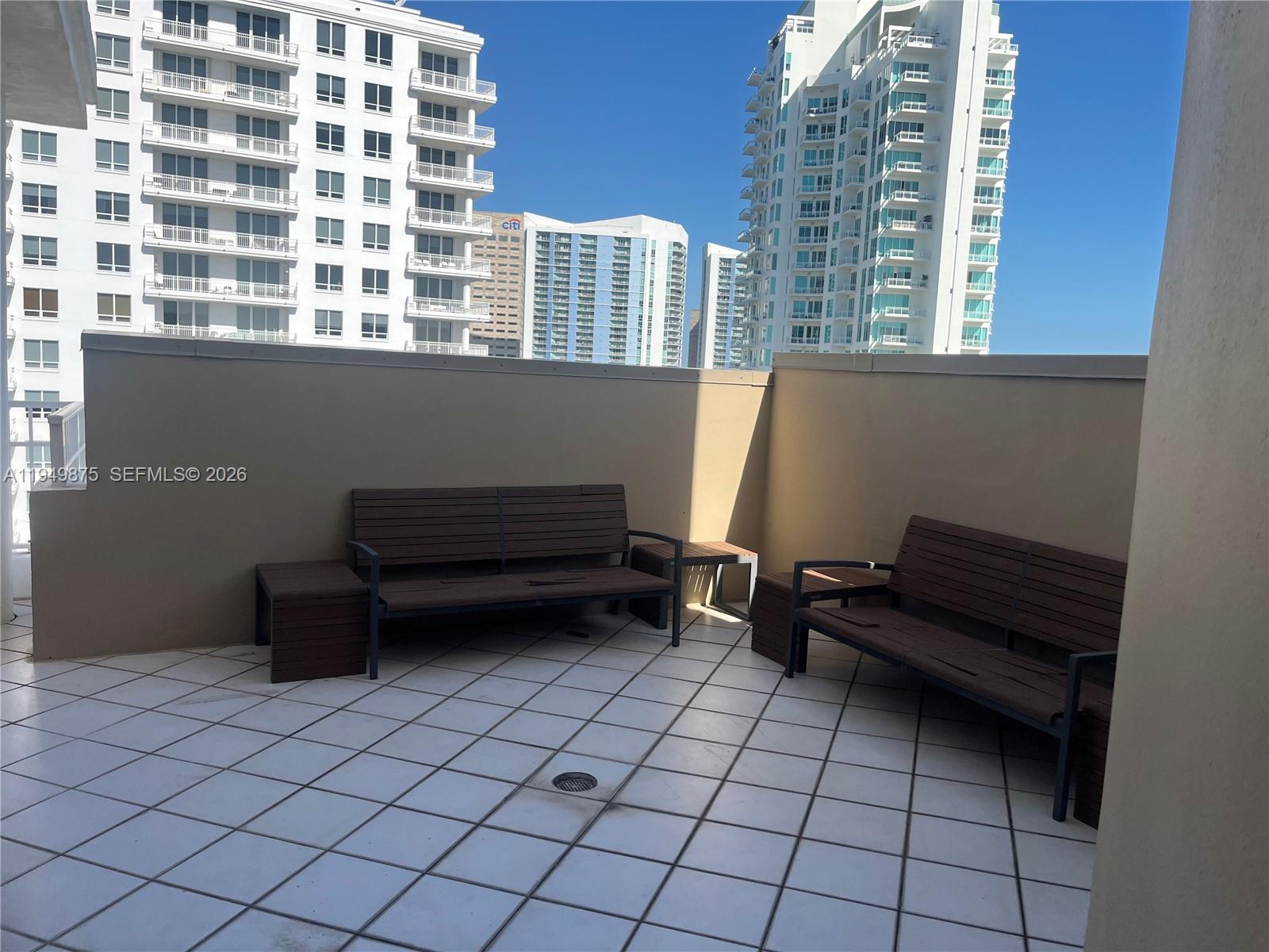 A balcony features two wooden benches with side tables on a tiled floor — 701 Brickell Key Blvd # 08, Miami FL 33131, MIAMI, FL