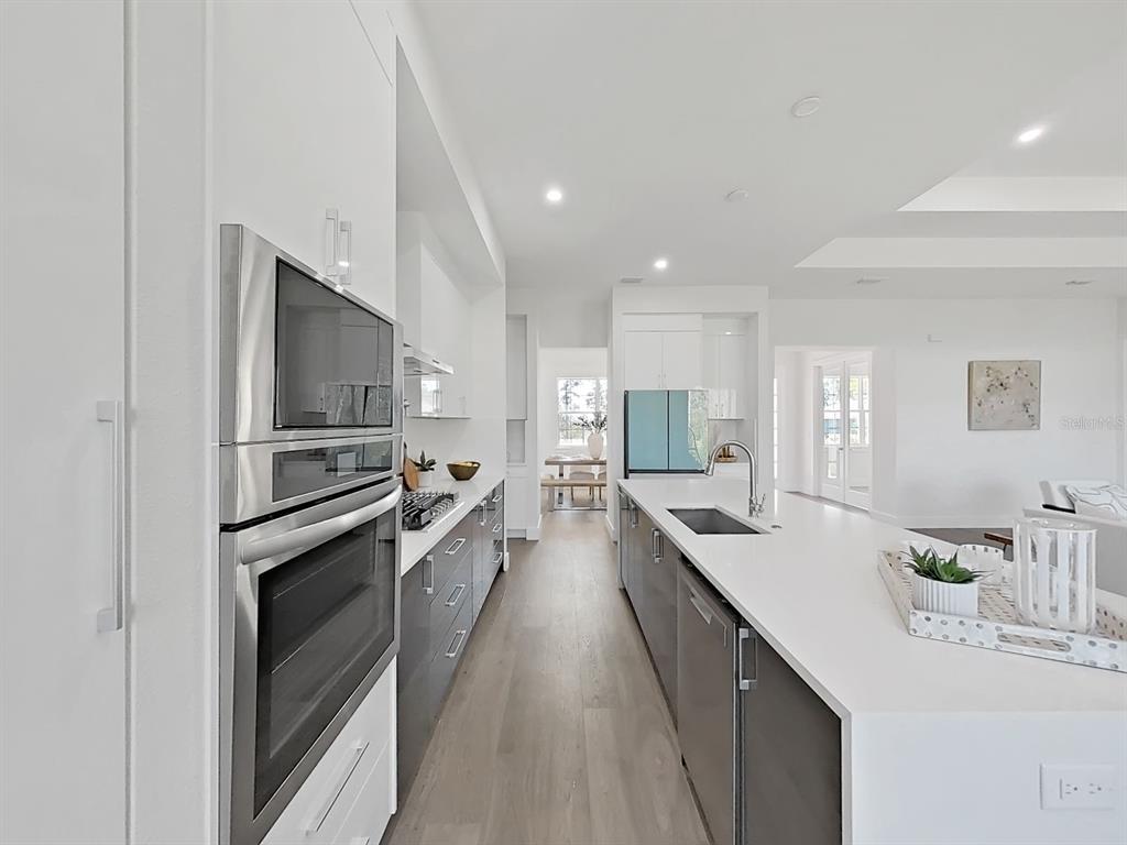 A modern kitchen features a large island, stainless steel appliances, and dark gray lower cabinets — 4716 HICKORY OAK DRIVE, BROOKSVILLE, FL