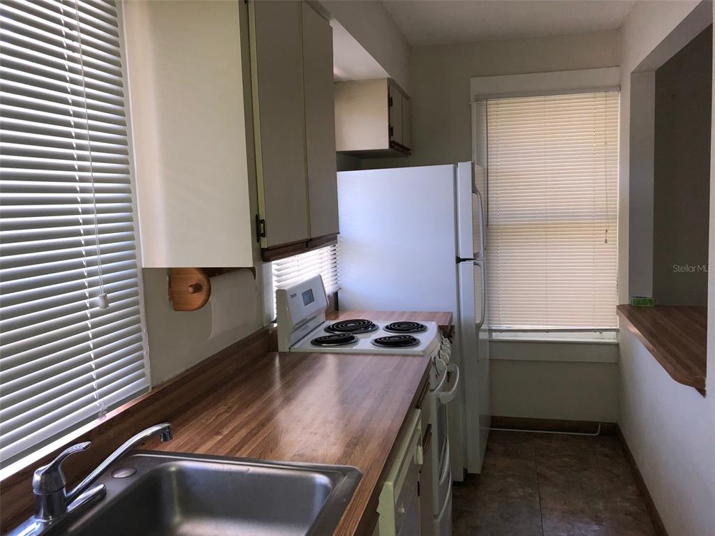 A galley kitchen features wood-look laminate countertops, white cabinets, and a white electric range — 1243 E RIDGEWOOD STREET, ORLANDO, FL