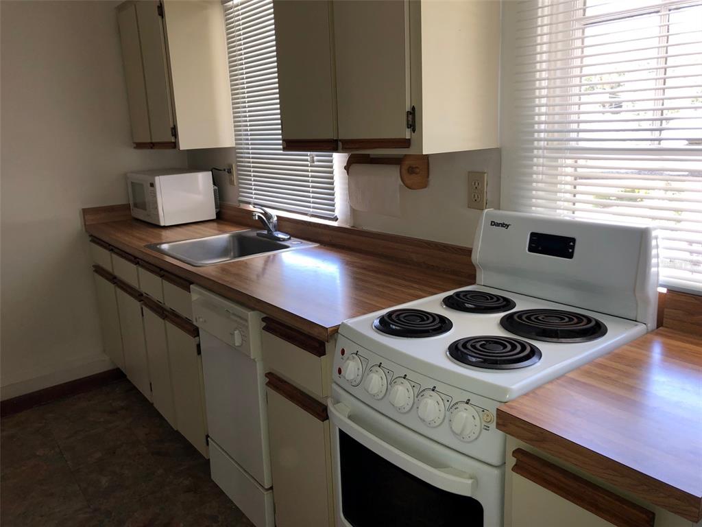 A kitchen features white cabinets, a wood-look countertop, a white stove, and a dishwasher — 1243 E RIDGEWOOD STREET, ORLANDO, FL