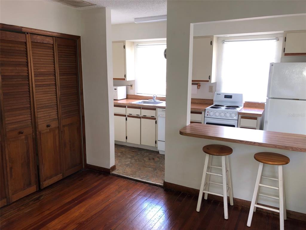 A kitchen with white cabinets and a breakfast bar overlooks a room with wood flooring — 1243 E RIDGEWOOD STREET, ORLANDO, FL