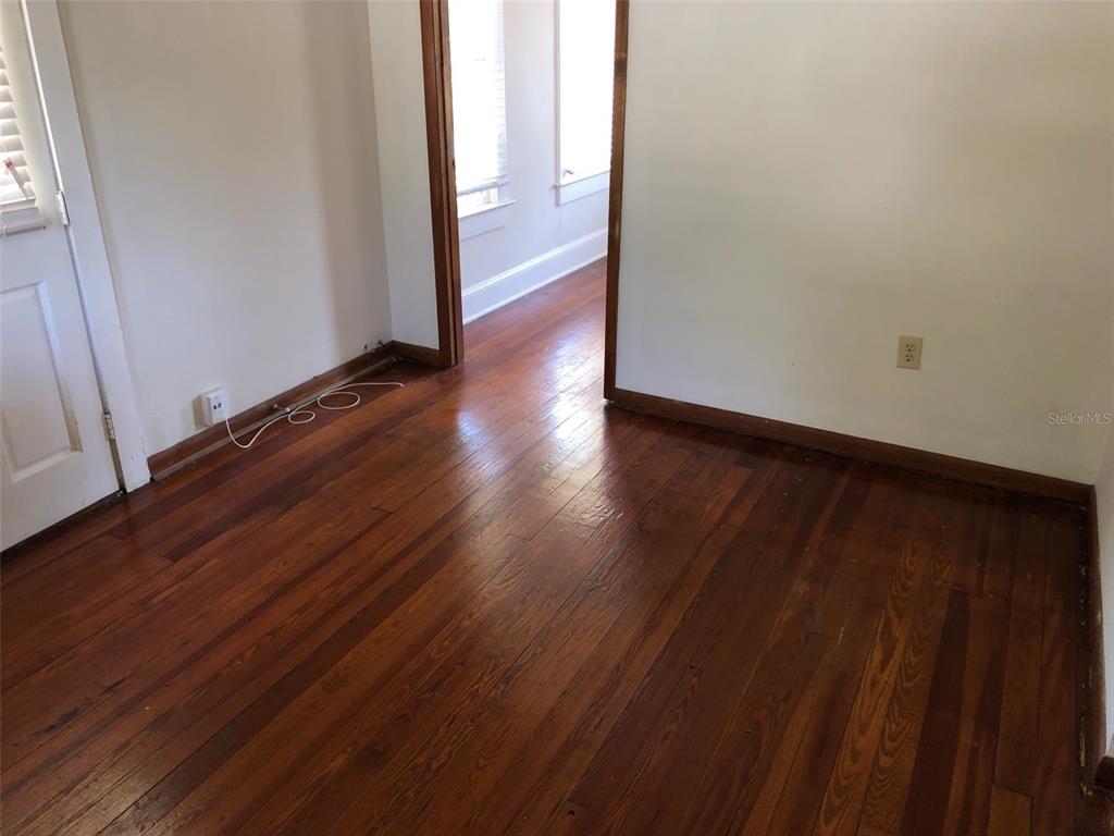 An empty room features hardwood floors, white walls, and a doorway leading to another space — 1243 E RIDGEWOOD STREET, ORLANDO, FL