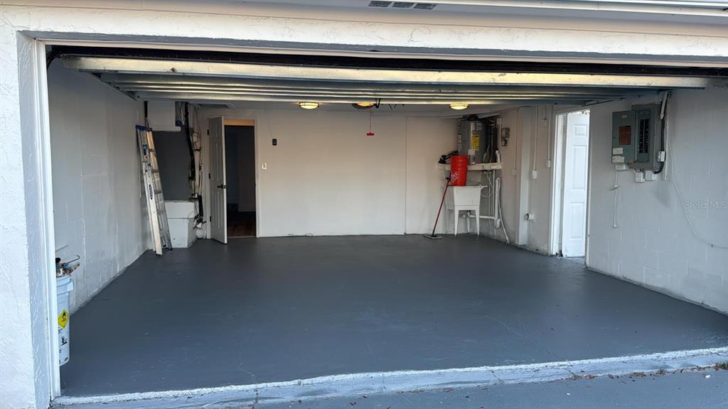 A two-car garage with a gray painted floor, white walls, and an open doorway — 1715 KENILWORTH STREET, HOLIDAY, FL