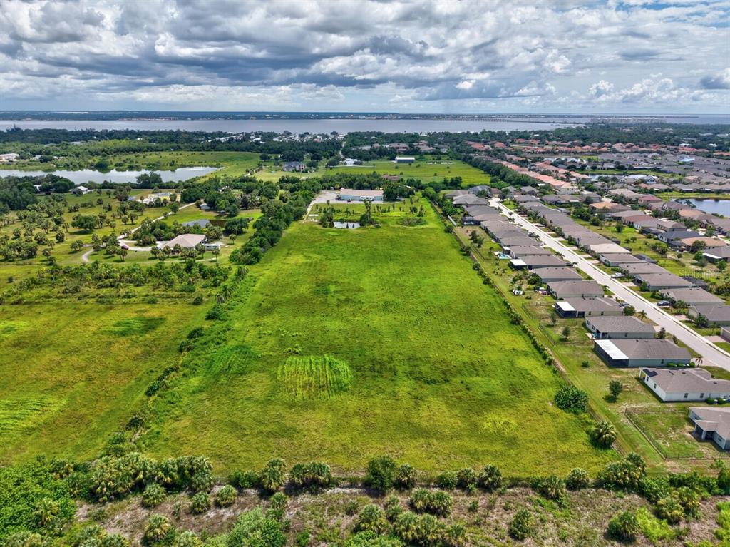 An aerial view shows a large, undeveloped grassy lot adjacent to a suburban residential neighborhood — 3400 ROWLAND DRIVE UNIT Tract A, PUNTA GORDA, FL