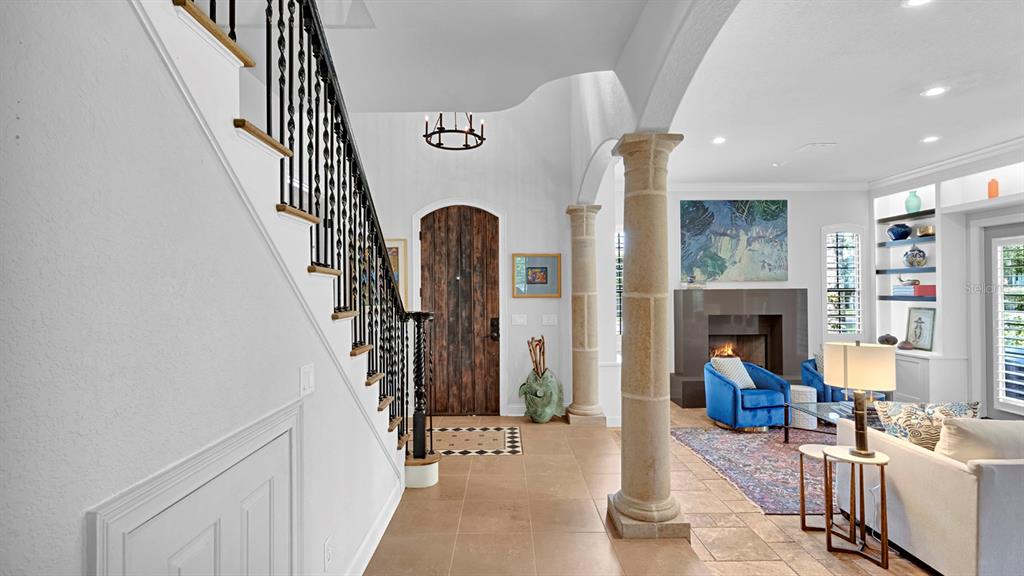 A foyer with a staircase and stone columns leads into a living room with a fireplace — 922 N PENNSYLVANIA AVENUE, WINTER PARK, FL