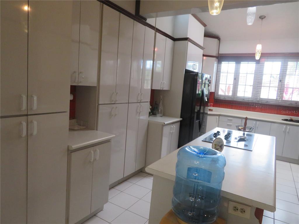 A kitchen features glossy white cabinetry, a central island with a cooktop, and tile flooring — Dorado del Mar PELICANO, DORADO, PR