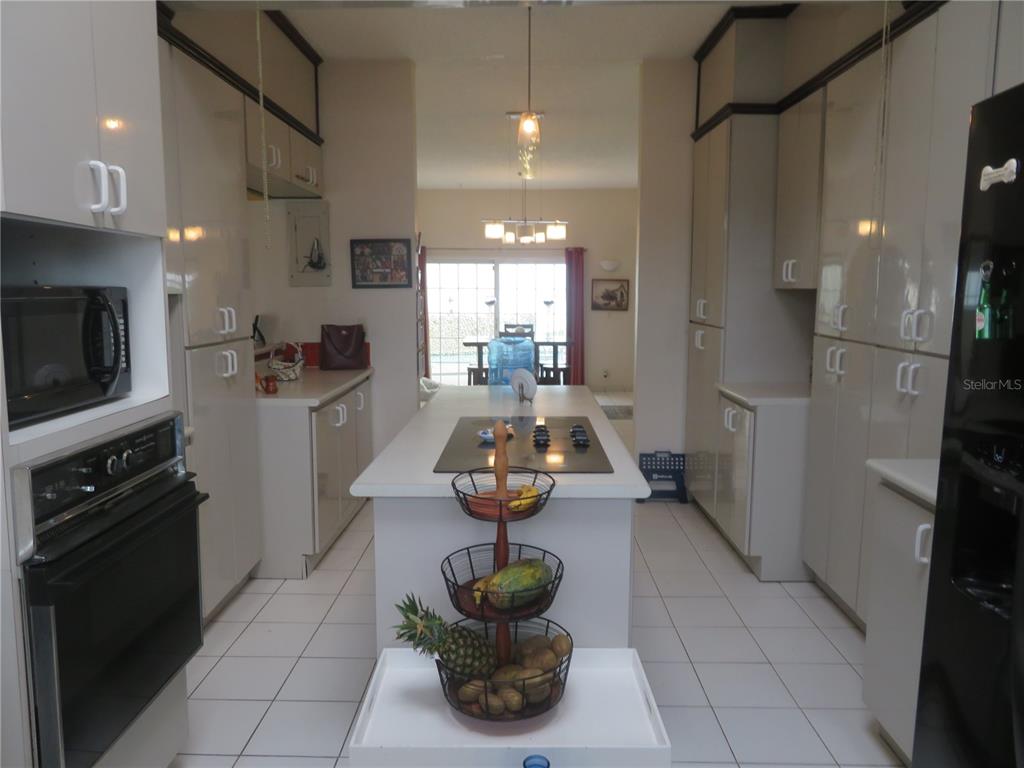 A galley kitchen features white cabinetry, a central island with a cooktop, and tile flooring — Dorado del Mar PELICANO, DORADO, PR