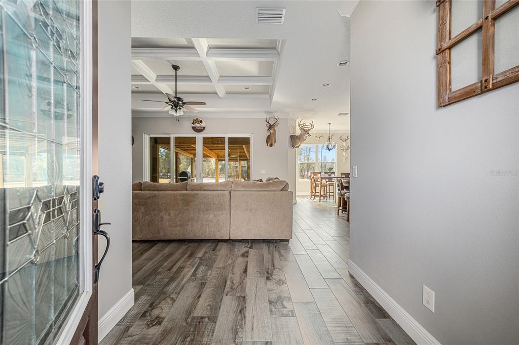A view from an entryway into a living room with wood-look tile and coffered ceilings — 8855 SW 129TH TERRACE ROAD, DUNNELLON, FL