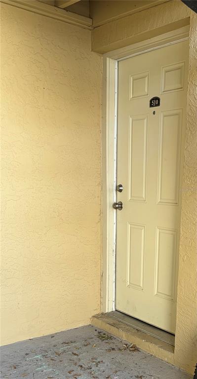 A light-colored exterior door labeled 510 is set into a textured, yellow-painted wall — 510 GOLDEN RAINTREE PLACE, BRANDON, FL