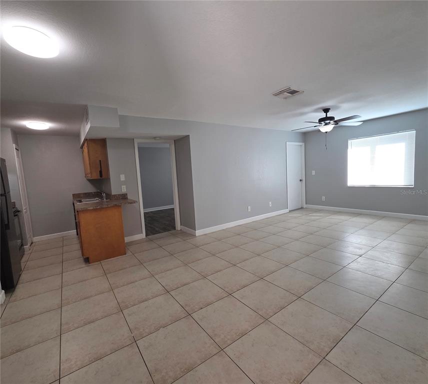 An open-concept living area features light gray walls, large beige floor tiles, and a kitchen — 510 GOLDEN RAINTREE PLACE, BRANDON, FL