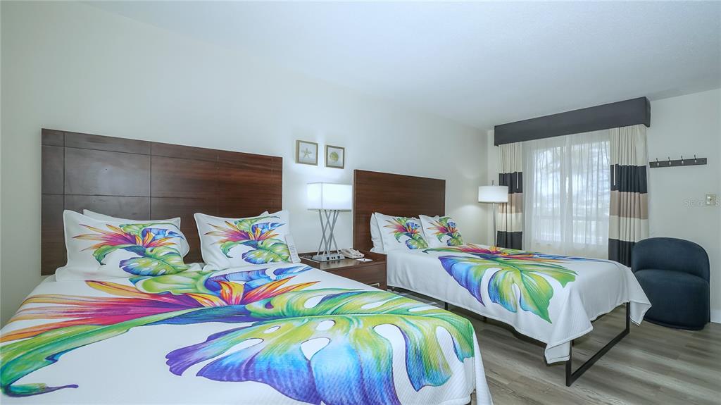 A bedroom features two beds with tropical-patterned bedding, dark wood headboards, and a blue chair — 7150 N TAMIAMI TRAIL UNIT S-600, SARASOTA, FL