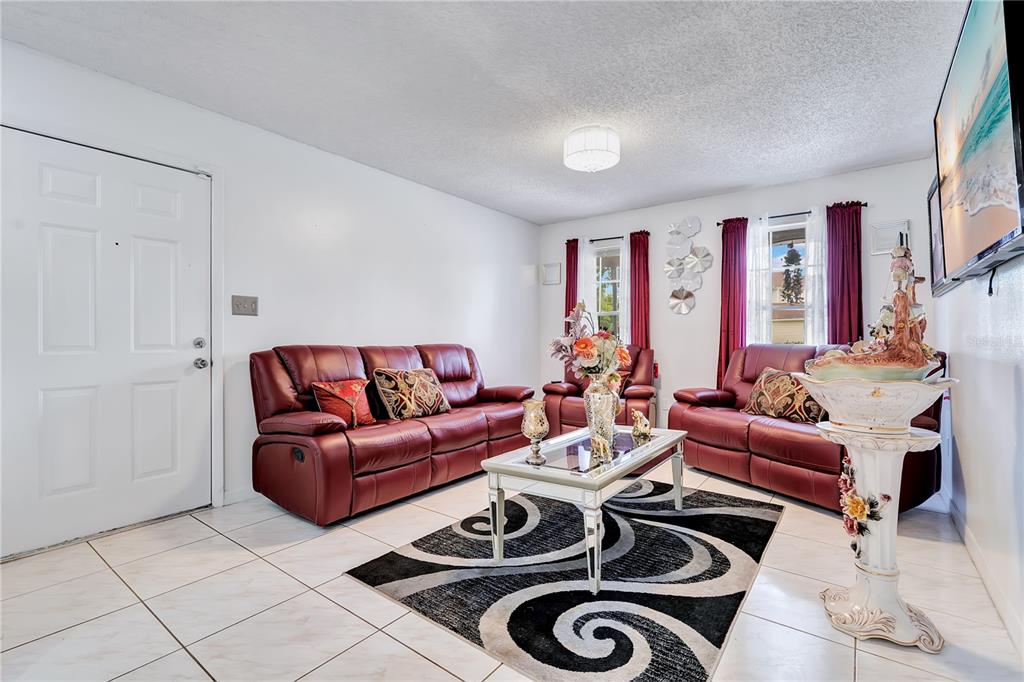 A living room features red leather sofas, a glass coffee table, and a patterned rug — 9824 SURREY RIDGE ROAD, ORLANDO, FL
