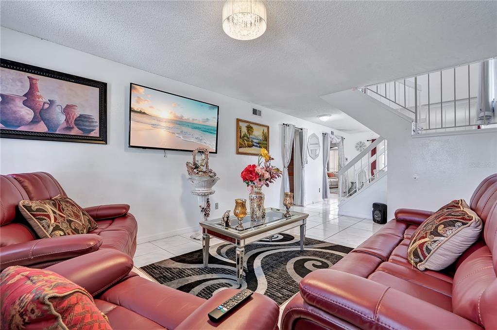 A living room features red leather sofas, a glass coffee table, and a staircase — 9824 SURREY RIDGE ROAD, ORLANDO, FL