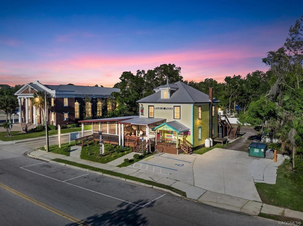 An exterior view of a yellow two-story building with a covered deck and parking lot — 125 N MAIN STREET, HASTINGS, FL