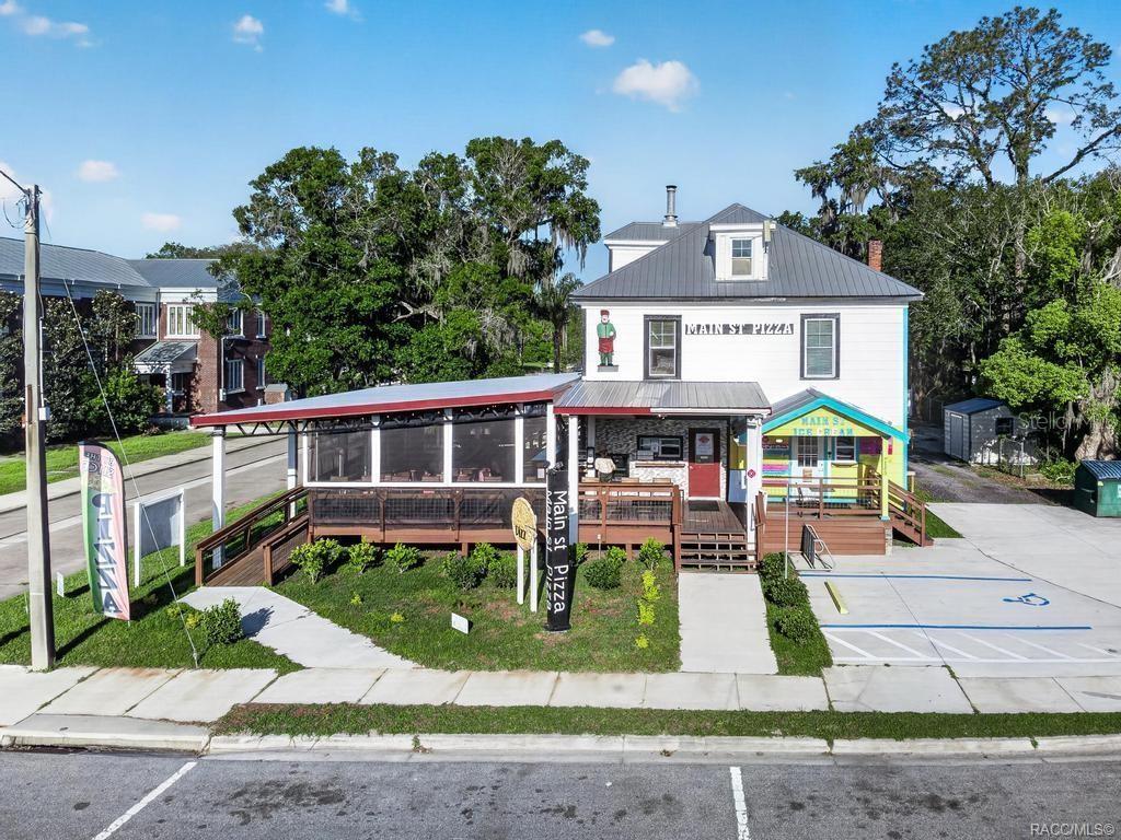 An exterior view of a two-story building with a covered deck and pizza restaurant signage — 125 N MAIN STREET, HASTINGS, FL