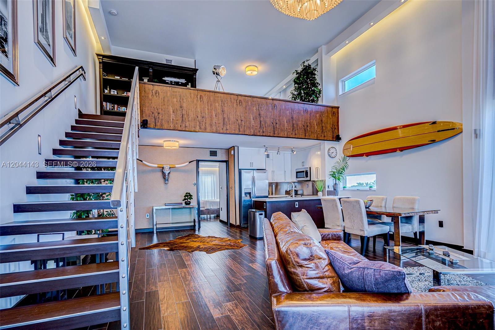 A modern open-concept living room features a wooden staircase, a loft area, and a kitchen — 1701 Sunset Harbour Dr # L507, Miami Beach FL 33139, MIAMI BEACH, FL