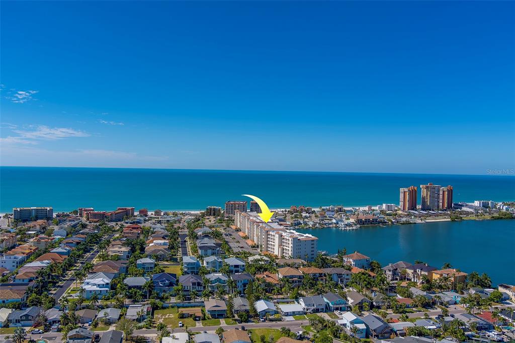 An aerial view shows a coastal neighborhood with a large apartment building near the water — 17735 GULF BOULEVARD UNIT 501, REDINGTON SHORES, FL