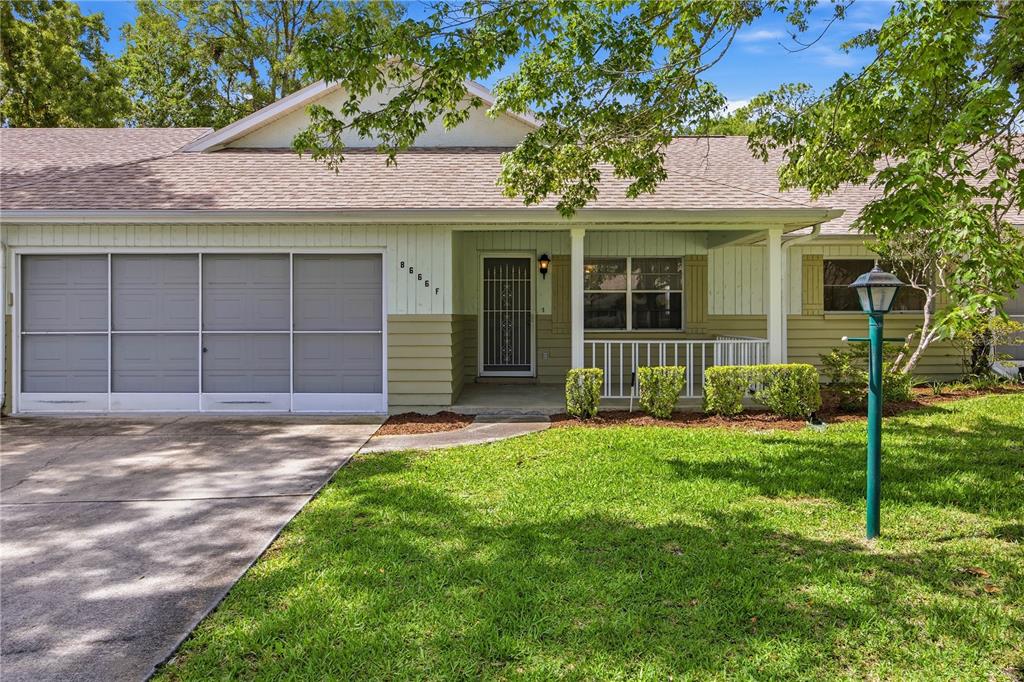 A single-story house with a screened-in garage, a front porch, and a green lawn — 8666 SW 92ND LANE UNIT F, OCALA, FL