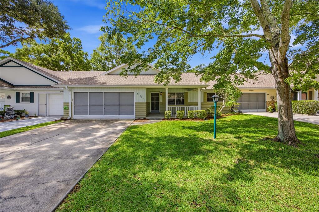 A single-story attached home features a concrete driveway, a screened garage, and a front porch — 8666 SW 92ND LANE UNIT F, OCALA, FL