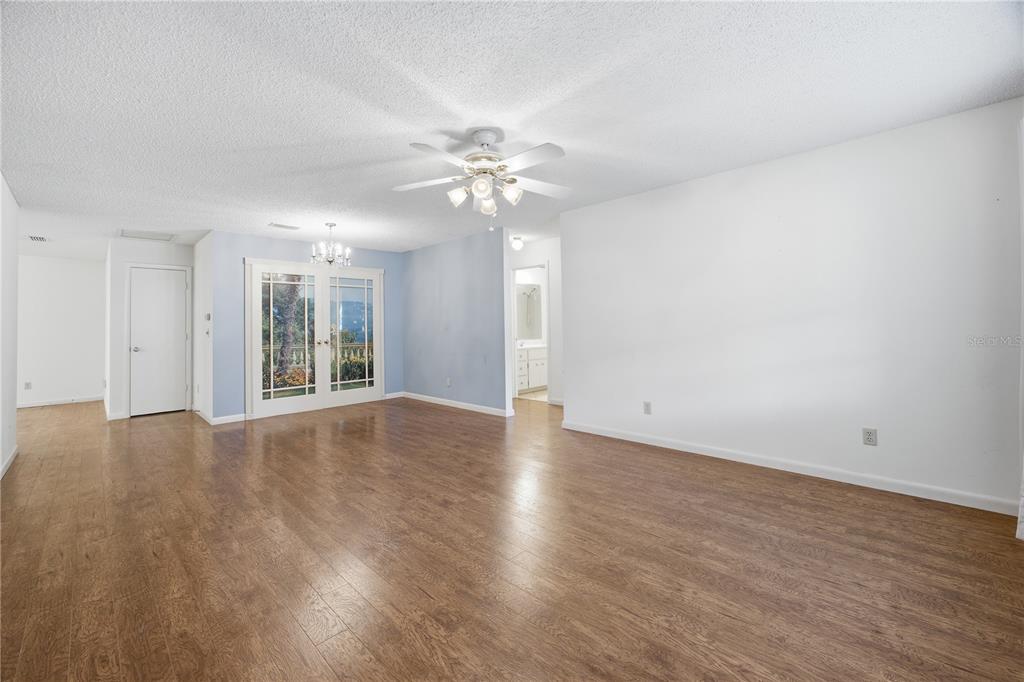 A spacious living room features wood-look flooring, a ceiling fan, and glass doors to outside — 8666 SW 92ND LANE UNIT F, OCALA, FL