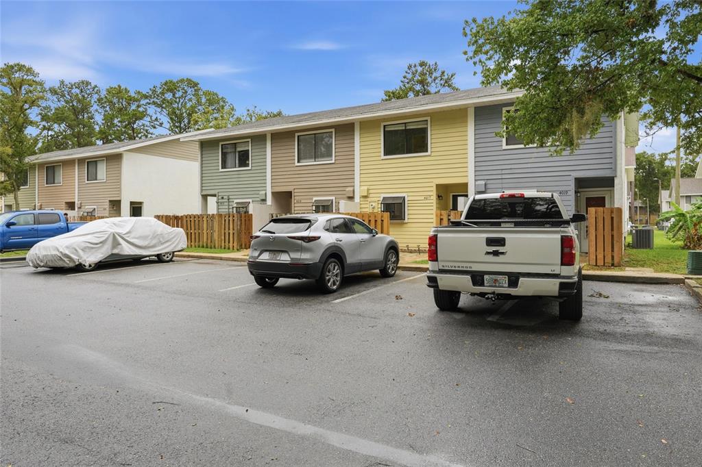 A row of multi-story townhomes with parking spaces in front and a silver pickup truck — 4017 SW 20TH LANE, GAINESVILLE, FL