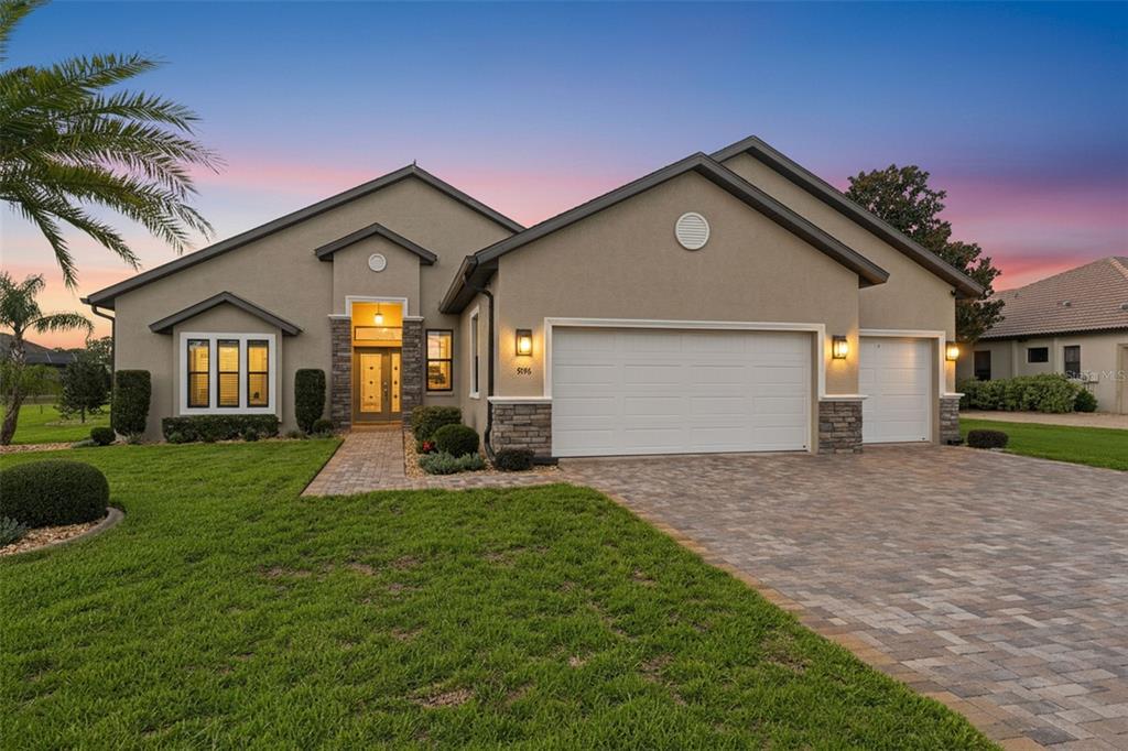 A single-story suburban house with a tan stucco exterior, stone accents, and a paved driveway — 9196 PALM BEACH DRIVE, BROOKSVILLE, FL
