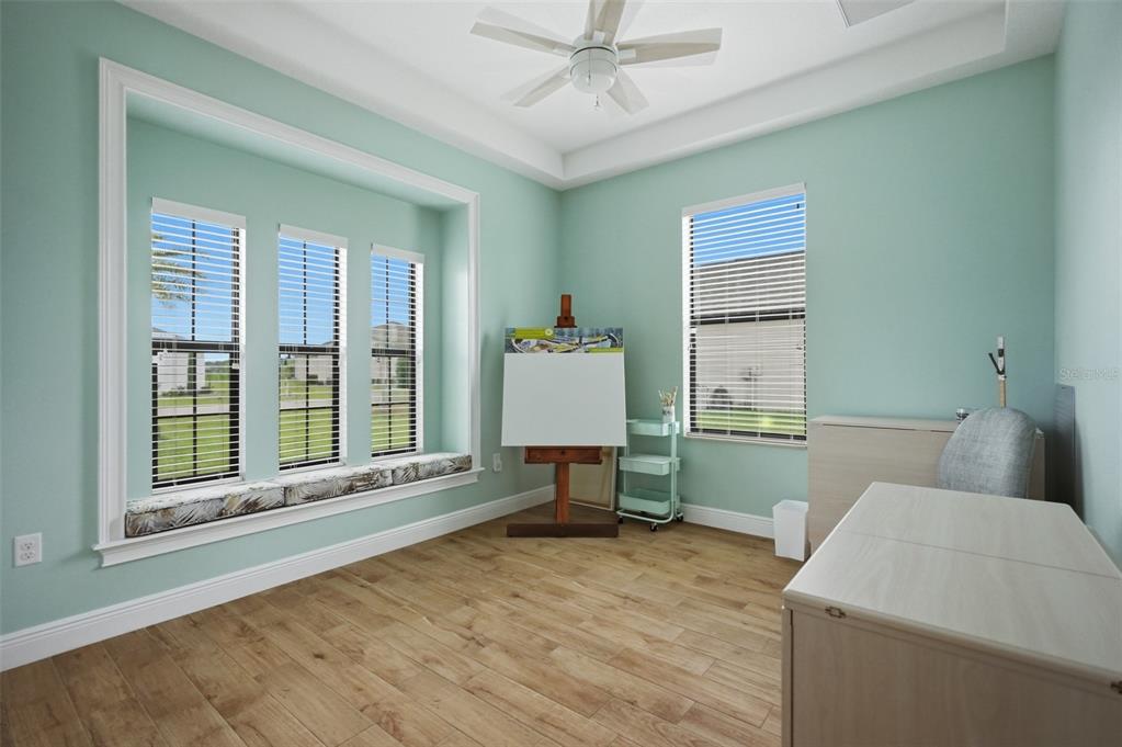 A light blue home office features a bay window, wood-look flooring, and an artist's easel — 9196 PALM BEACH DRIVE, BROOKSVILLE, FL