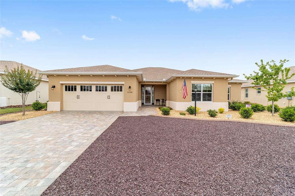 A single-story house with a tan stucco exterior, a two-car garage, and a paved driveway — 10344 SW 98TH PLACE ROAD, OCALA, FL